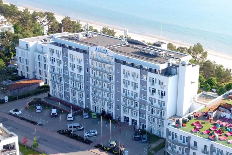 Aufnahme aus der Luft des Arkona Strandhotel direkt am Meer, im Hintergrund Bäume und der Strand.
