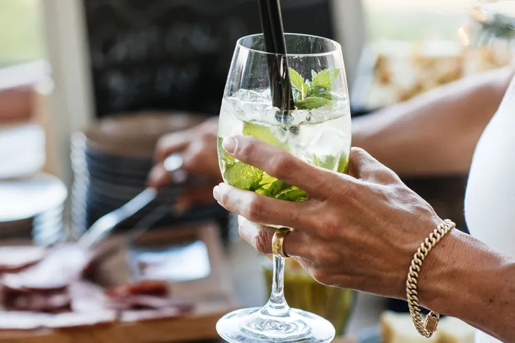 Detailaufnahme einer Frau, die einen Cocktail in der Hand hält bei einem Bankett im Arkona Strandhotel in Binz auf Rügen.