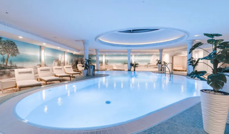 Großer Innenpool im Arkona Strandhotel Binz auf Rügen mit Liegen, Säulen und hellem Wellnessbereich