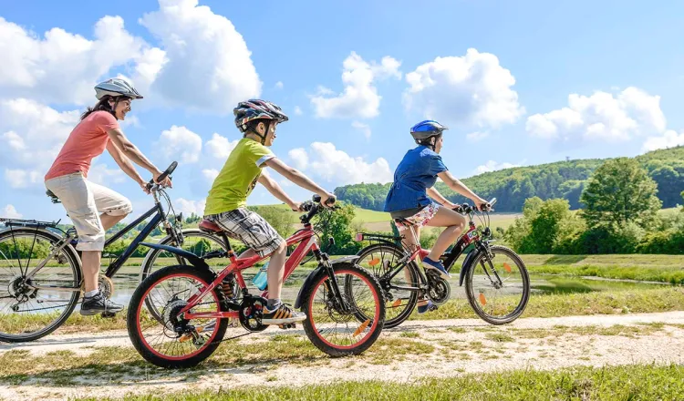 Eine Familie genießt die Landschaft bei Sonnenschein auf einer spontanen Fahrradtour mit Leihrädern.