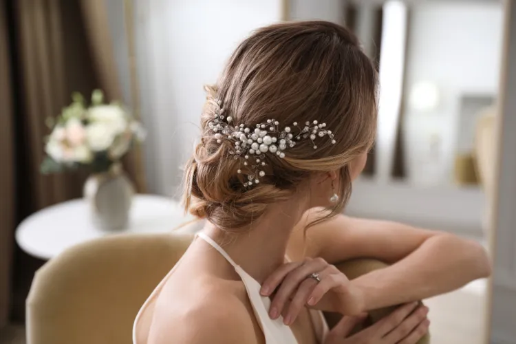 Eine Braut hatte ein Brautstyling in Binz und hat einen wunderschönen, weißen Hochzeitsschmuck in ihrer Hochsteckfrisur.