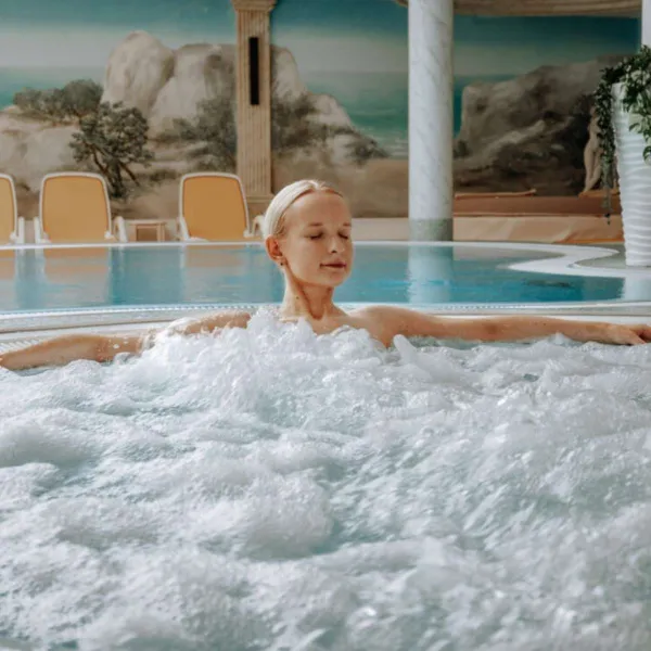 Eine Frau entspannt in einem Whirlpool in einem Wellnesshotel bei einem Angebot an der Ostsee.
