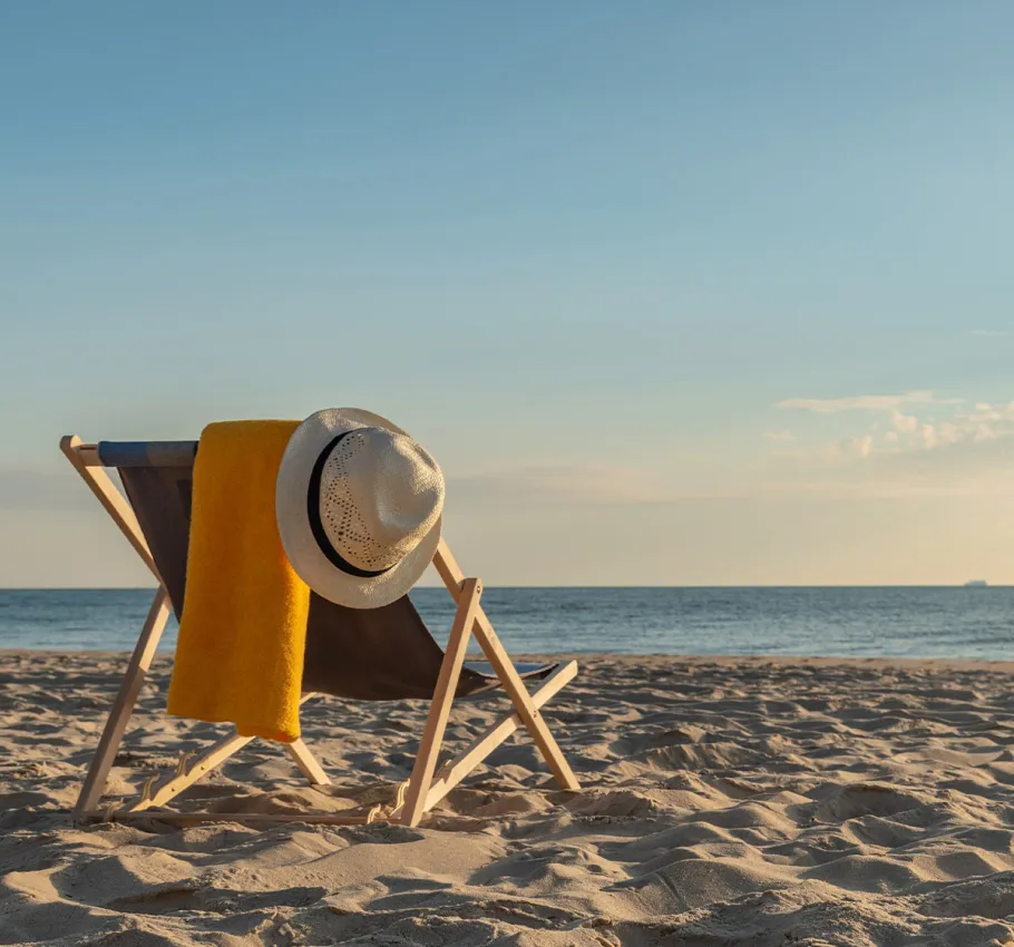 Ein gemütlicher Liegestuhl mit einem Sonnenhut und einem Handtuch am Ostseestrand in Binz bei sonnigem Wetter.
