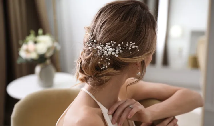 Eine Braut hatte ein Brautstyling in Binz und hat einen wunderschönen, weißen Hochzeitsschmuck in ihrer Hochsteckfrisur.