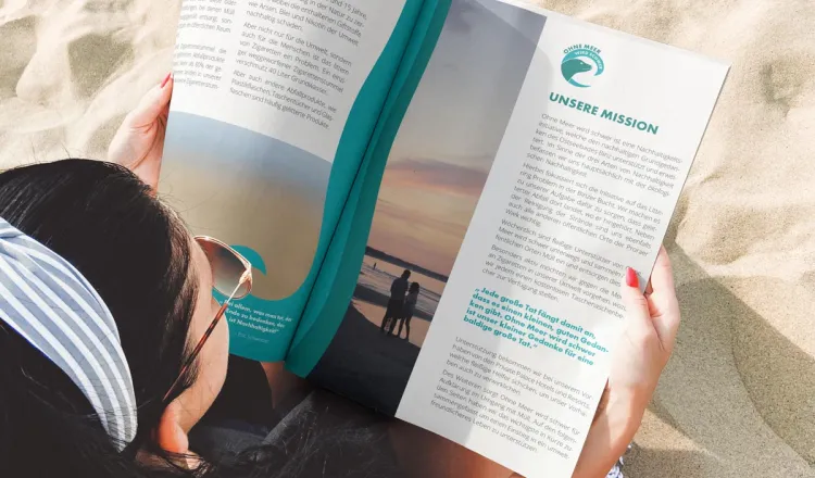 Frau liest das OMWS-Magazin am Strand von Binz – Arkona Strandhotel engagiert sich mit der Initiative „Ohne Meer wird schwer“ für Umweltschutz