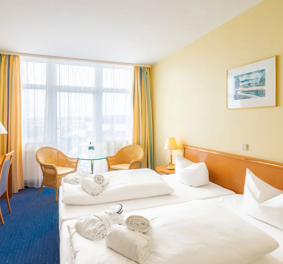 Doppelzimmer geeignet als Familienzimmer an der Ostsee mit zwei Betten, heller Einrichtung und Blick auf den Stadtbalkon.