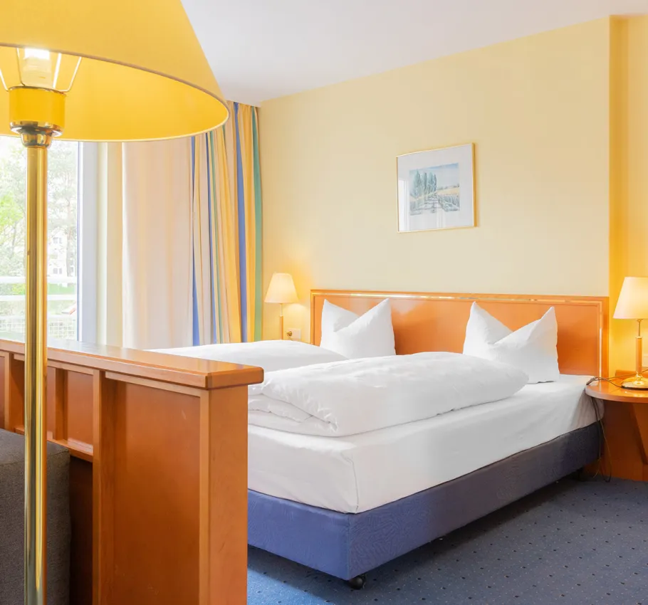 Junior Suite geeignet als Familienzimmer an der Ostsee mit Doppelbett, gemütlicher Beleuchtung und Blick auf die Stadt.