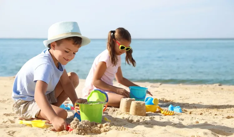 Kinder bauen Sandburgen am Strand von Rügen während eines Familienurlaubs.