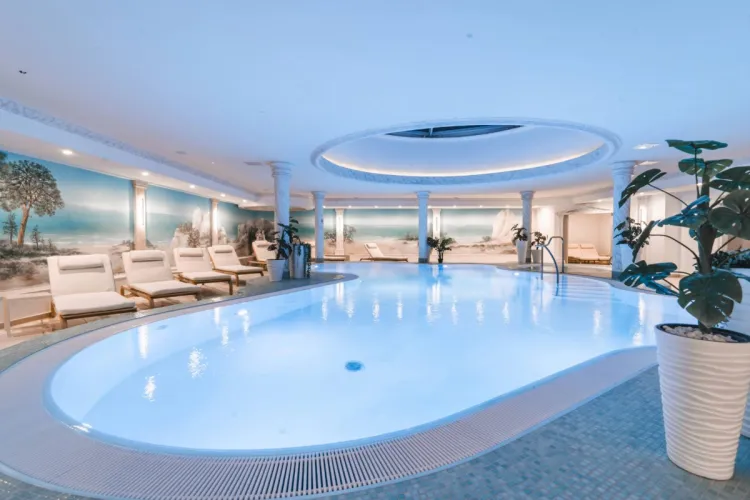 Großer Innenpool im Arkona Strandhotel Binz auf Rügen mit Liegen, Säulen und hellem Wellnessbereich