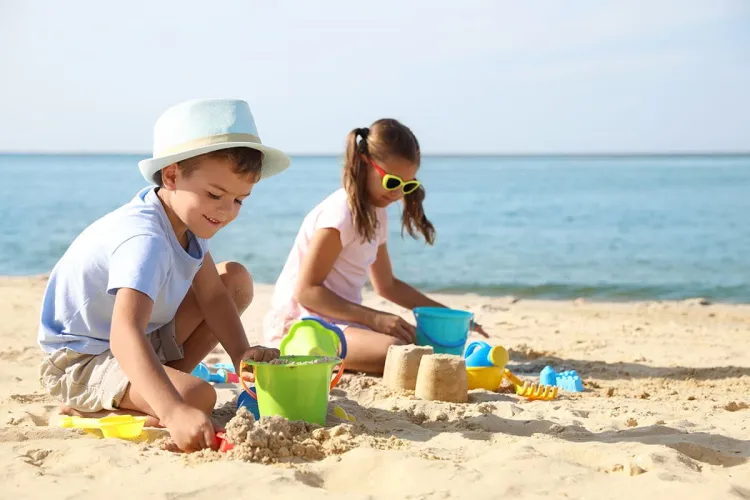 Kinder bauen Sandburgen am Strand von Rügen während eines Familienurlaubs.