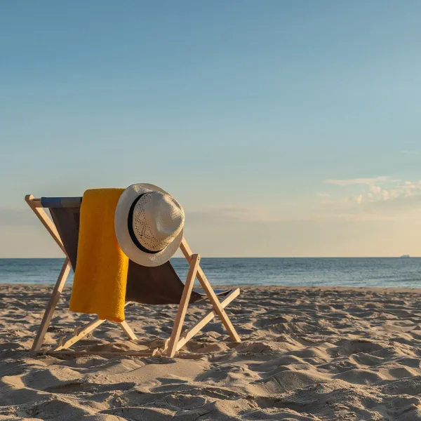 A cozy deck chair with a sun hat and a towel on the Baltic Sea beach in Binz in sunny weather.