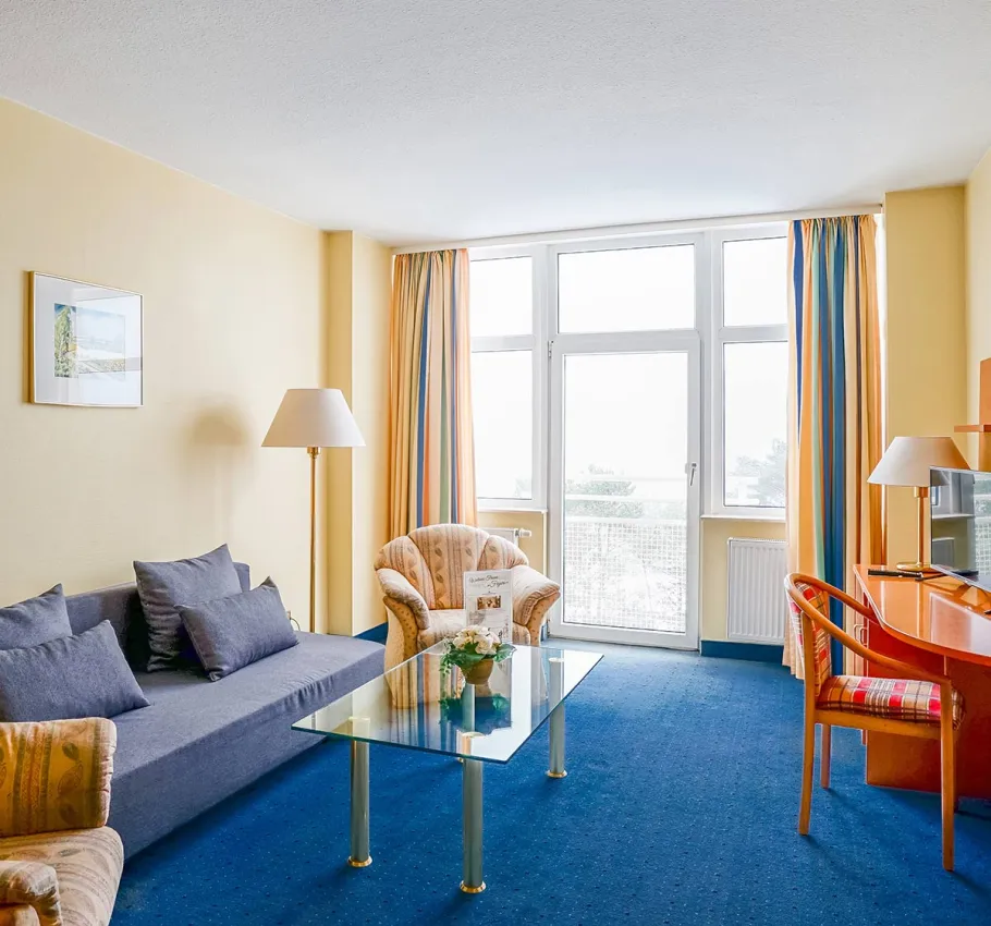 Suite im Arkona Strandhotel Binz mit Sitzecke, Glastisch und Blick auf den Balkon geeignet als Familienzimmer an der Ostsee.