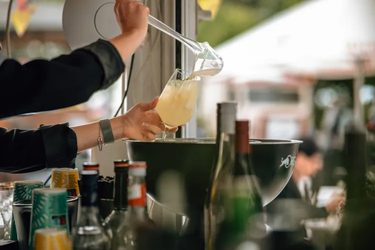 Barkeeperin gießt ein erfrischendes Getränk in ein Glas in der Rooftop Bar des Arkona Strandhotels in Binz.