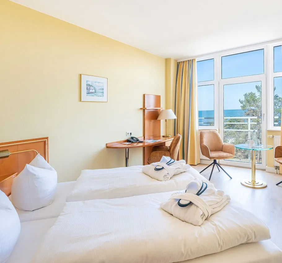 Doppelzimmer im Arkona Strandhotel Binz mit zwei Einzelbetten, Ostsee Meerblick und gemütlicher Sitzecke.