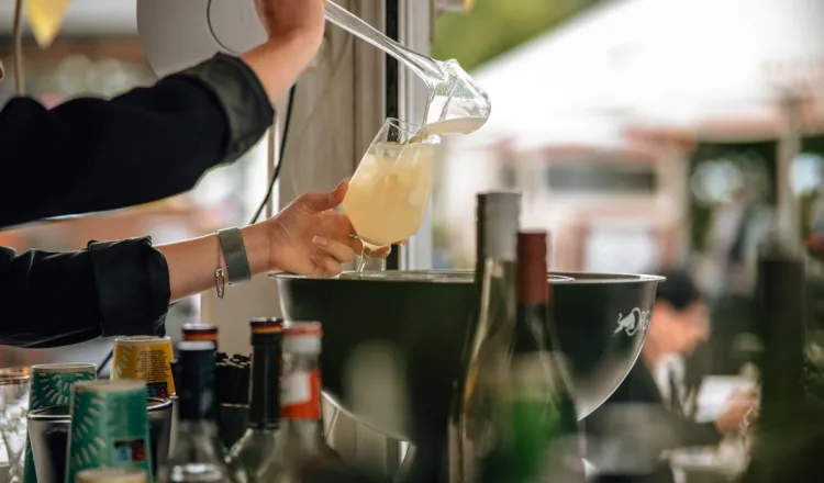 Barkeeperin gießt ein erfrischendes Getränk in ein Glas in der Rooftop Bar des Arkona Strandhotels in Binz.