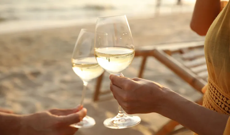 Paar stößt mit Weißwein am Strand von Binz an – Teil des Green Stay-Programms im Arkona Strandhotel auf Rügen