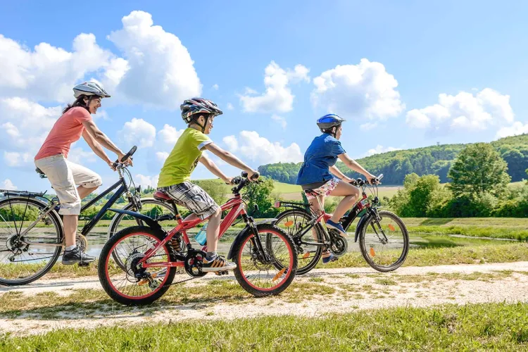 Eine Familie genießt die Landschaft bei Sonnenschein auf einer spontanen Fahrradtour mit Leihrädern.