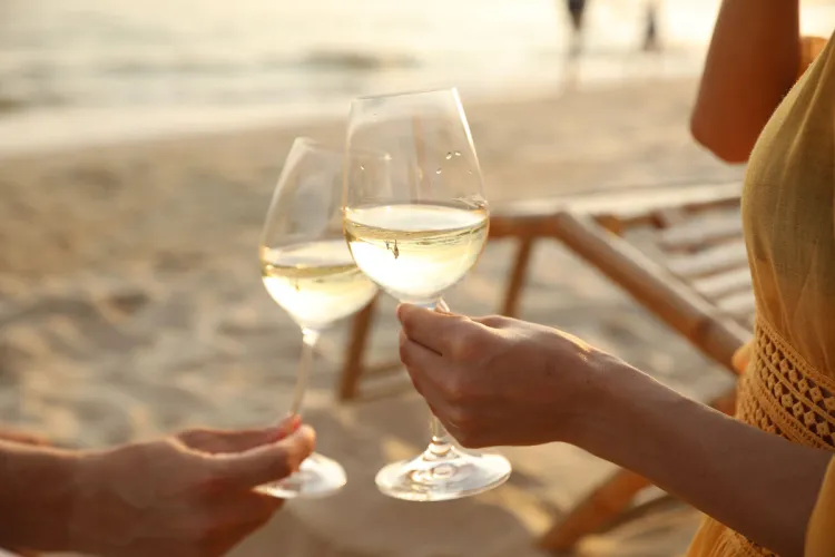 Paar stößt mit Weißwein am Strand von Binz an – Teil des Green Stay-Programms im Arkona Strandhotel auf Rügen