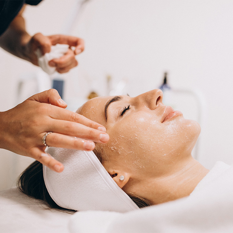 Eine Frau mit geschlossenen Augen erhält im Arkona Strandhotel Rügen eine Gesichtsbehandlung mit Peeling im Rahmen der Biodroga Organic Pflege