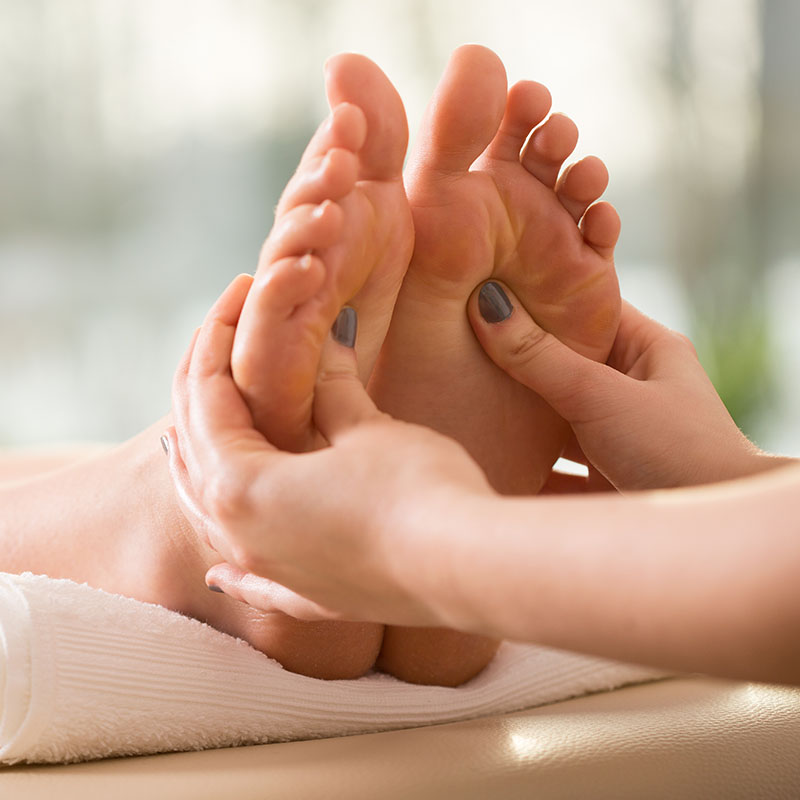 Die Füße einer Frau werden während einer Massageanwendung an der Ostsee massiert.