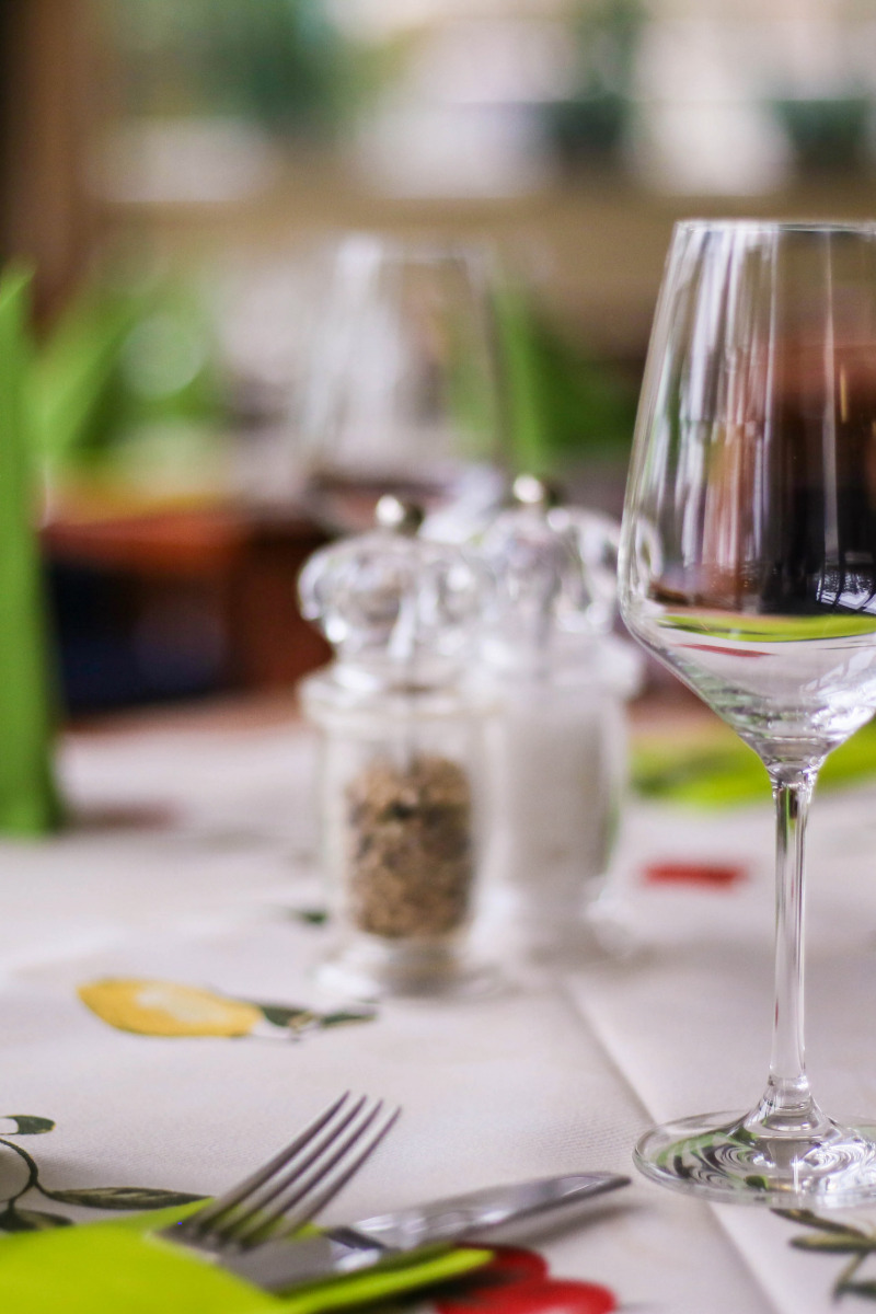 Ein festlich gedeckter Tisch mit Weingläsern und frühlingshafter grüner Tischdeko im Arkona Strandhotel.