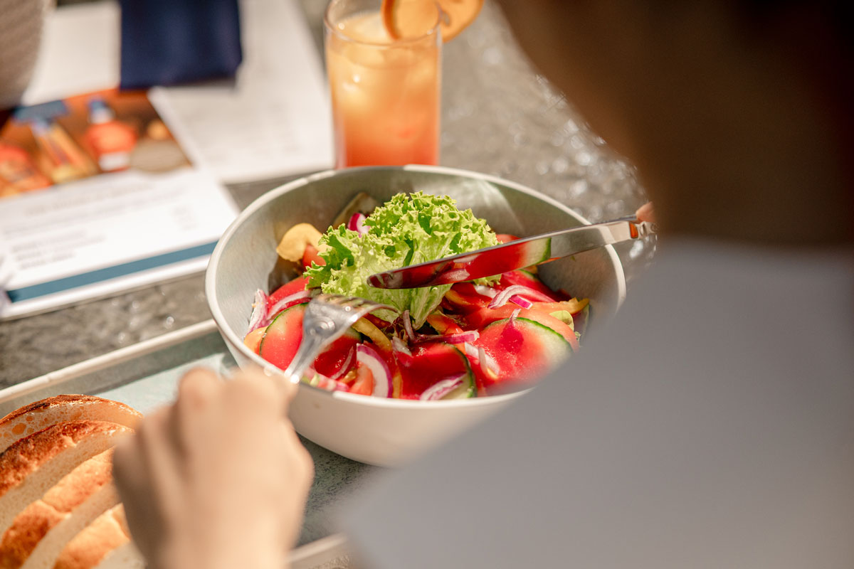 Woman enjoying colorful salad on the terrace of Arkona Strandhotel in Binz – with regional ingredients from the island of Rügen