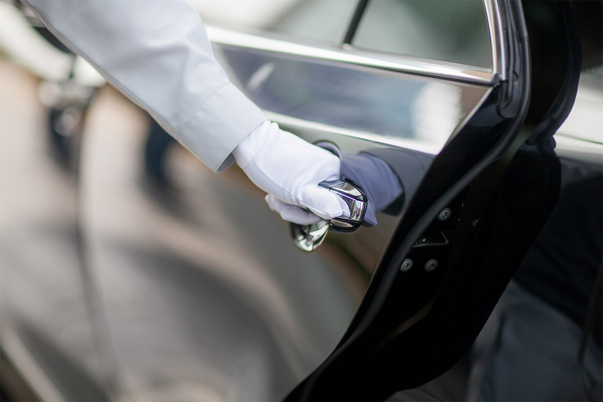 The chauffeur opens the door of the elegant limousine of the Arkona Strandhotel.