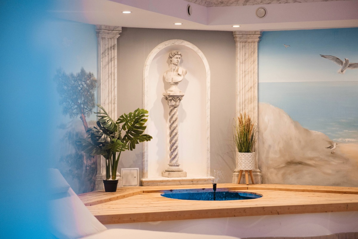 Dekorativer Wellnessbereich im Arkona Strandhotel Binz auf Rügen mit Säulen, Skulptur und Wandmotiv am Pool