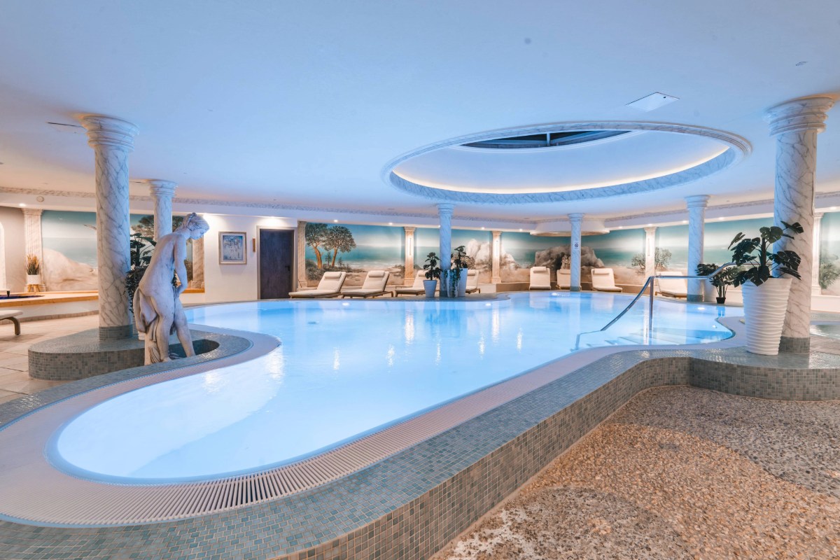 Großer Innenpool im Wellnessbereich des Arkona Strandhotels Binz auf Rügen mit Säulen, Skulptur und Liegen