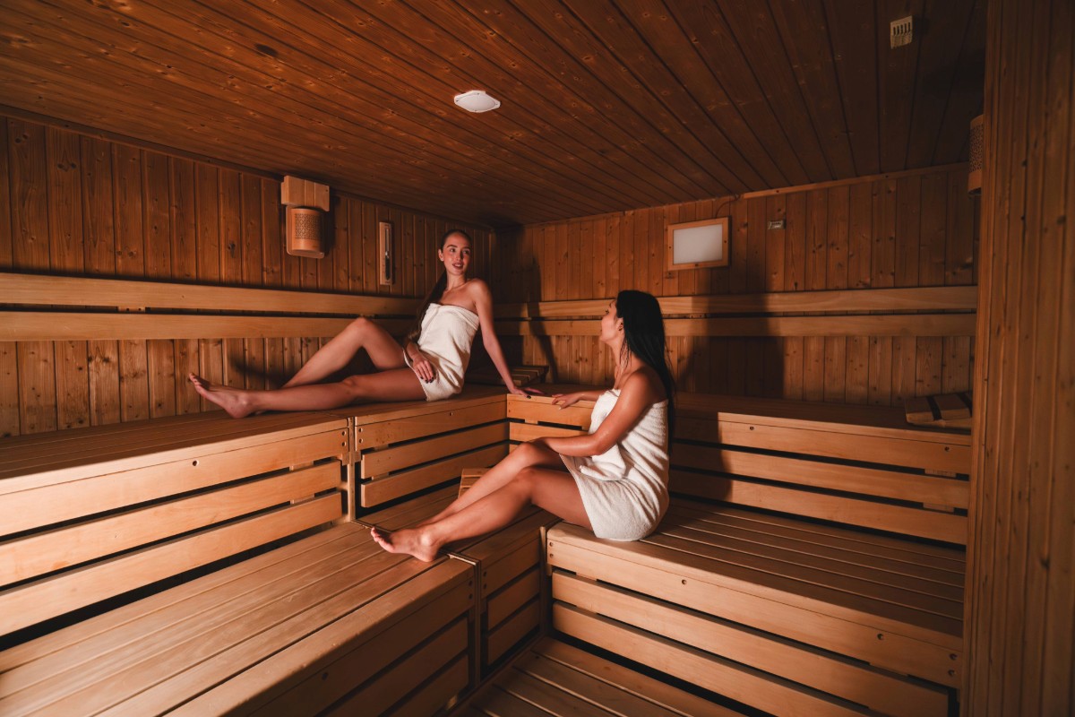 Zwei Damen sitzen in der Sauna des Arkona Strandhotels Binz auf Rügen auf Holzbänken
