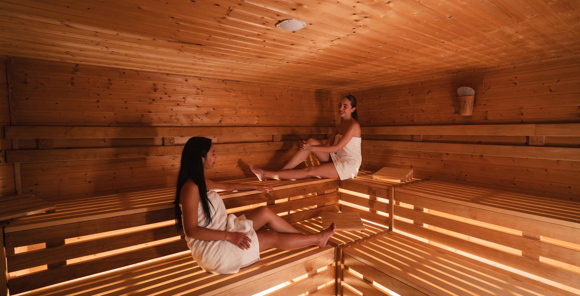 Zwei Damen sitzen in der Sauna des Arkona Strandhotels Binz auf Rügen auf Holzbänken aus hellem Holz