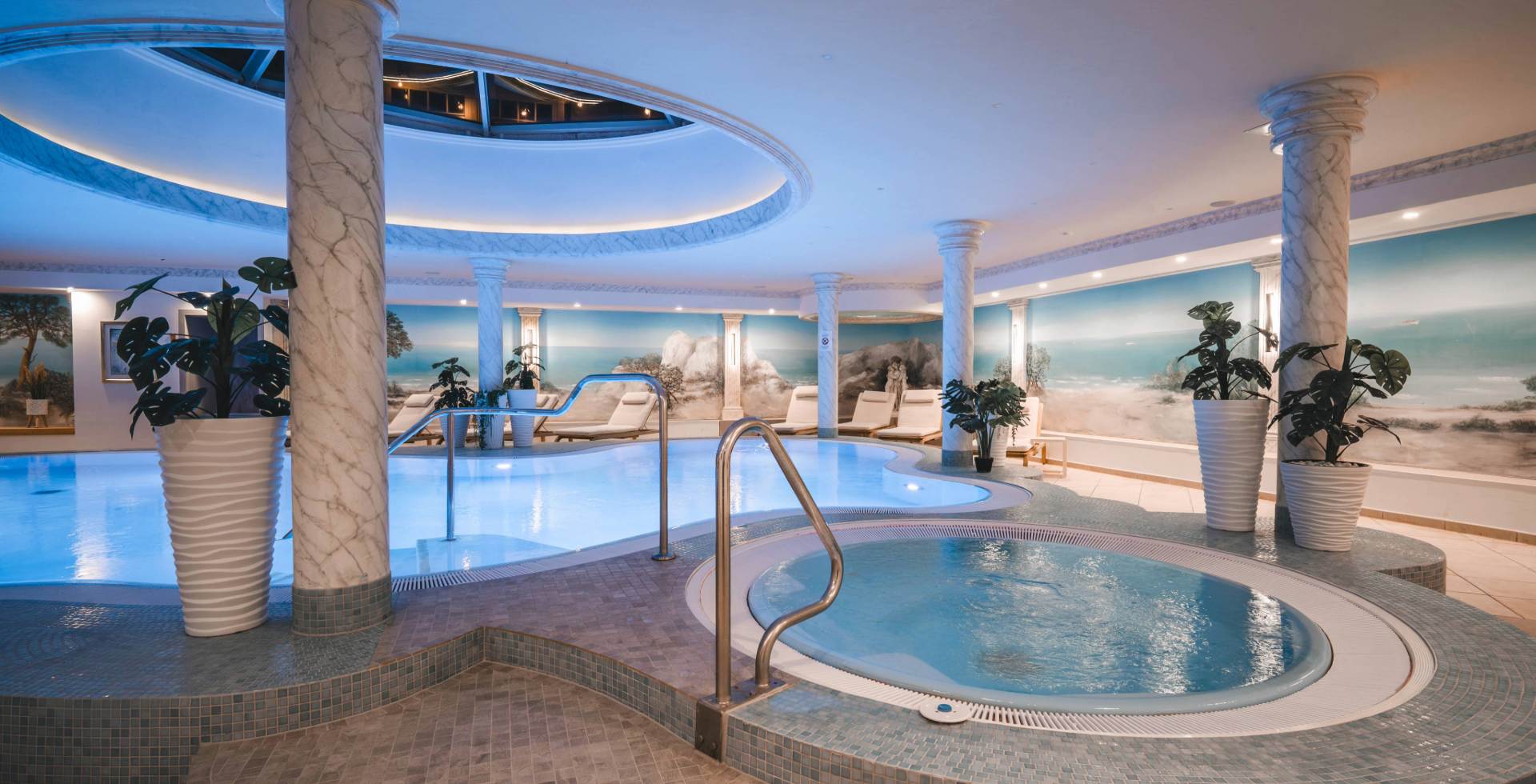 Pool und Whirlpool im Wellnessbereich des Arkona Strandhotels Binz auf Rügen mit Säulen, Liegen und Wasserzugang