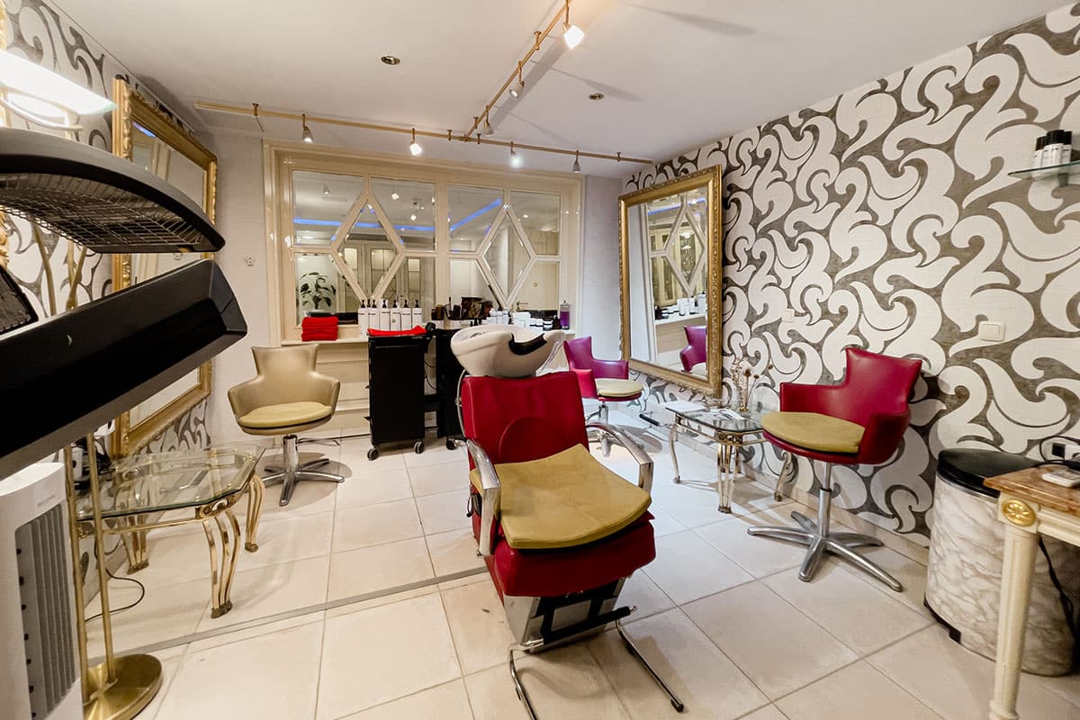 Exklusiver Friseursalon mit roten Sesseln und goldenen Akzenten im Spa Hotel auf Rügen.